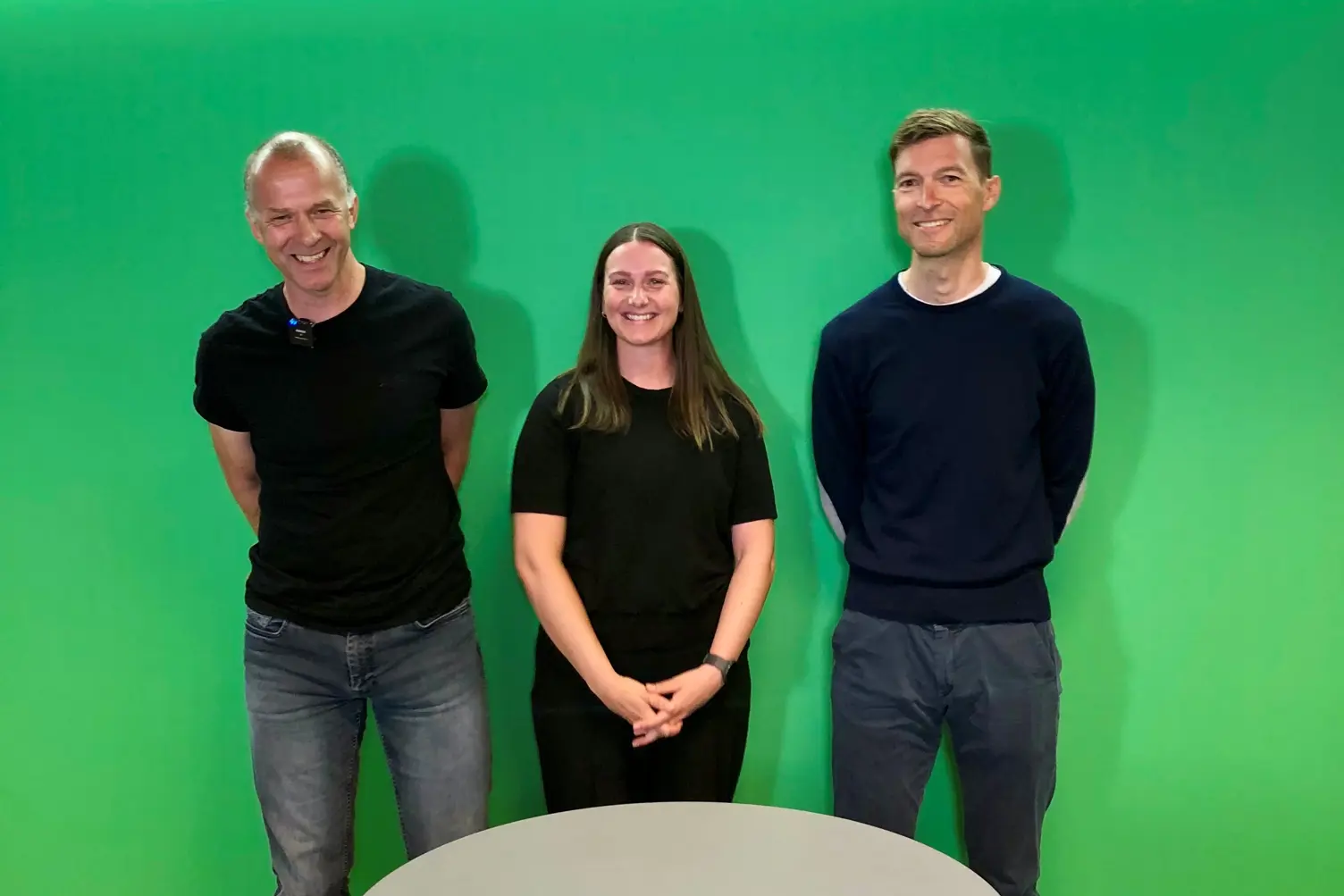 En gruppe mennesker som står foran en grønn vegg