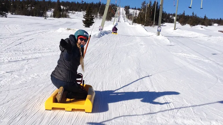 En person på en kjelke blir tatt opp bakken med heis