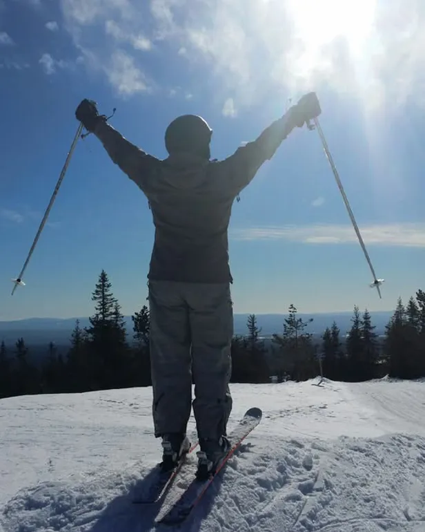 En person står på ski og nyter solen
