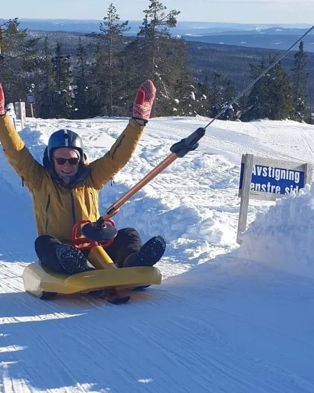 En person på kjelke kjører opp bakken med heis