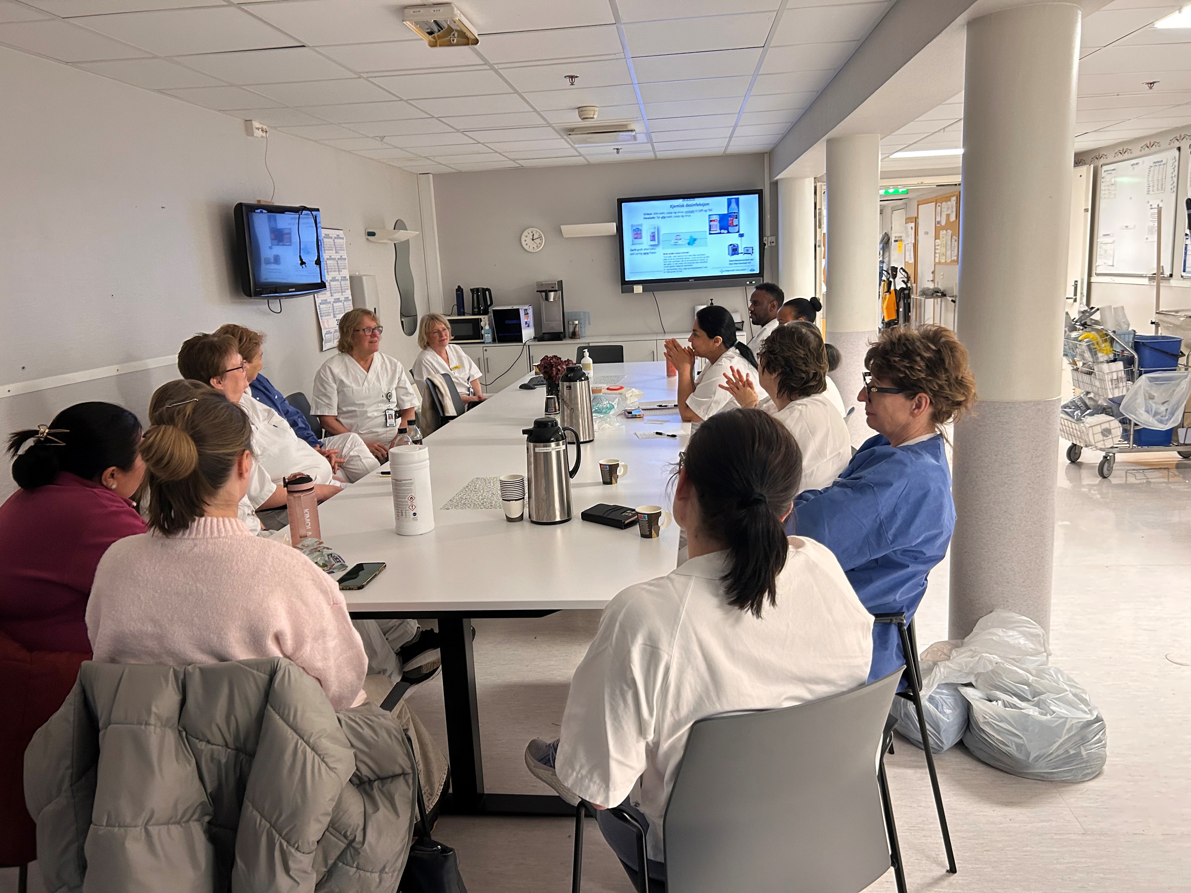 En gruppe mennesker som sitter rundt et bord og ser på en presentasjon