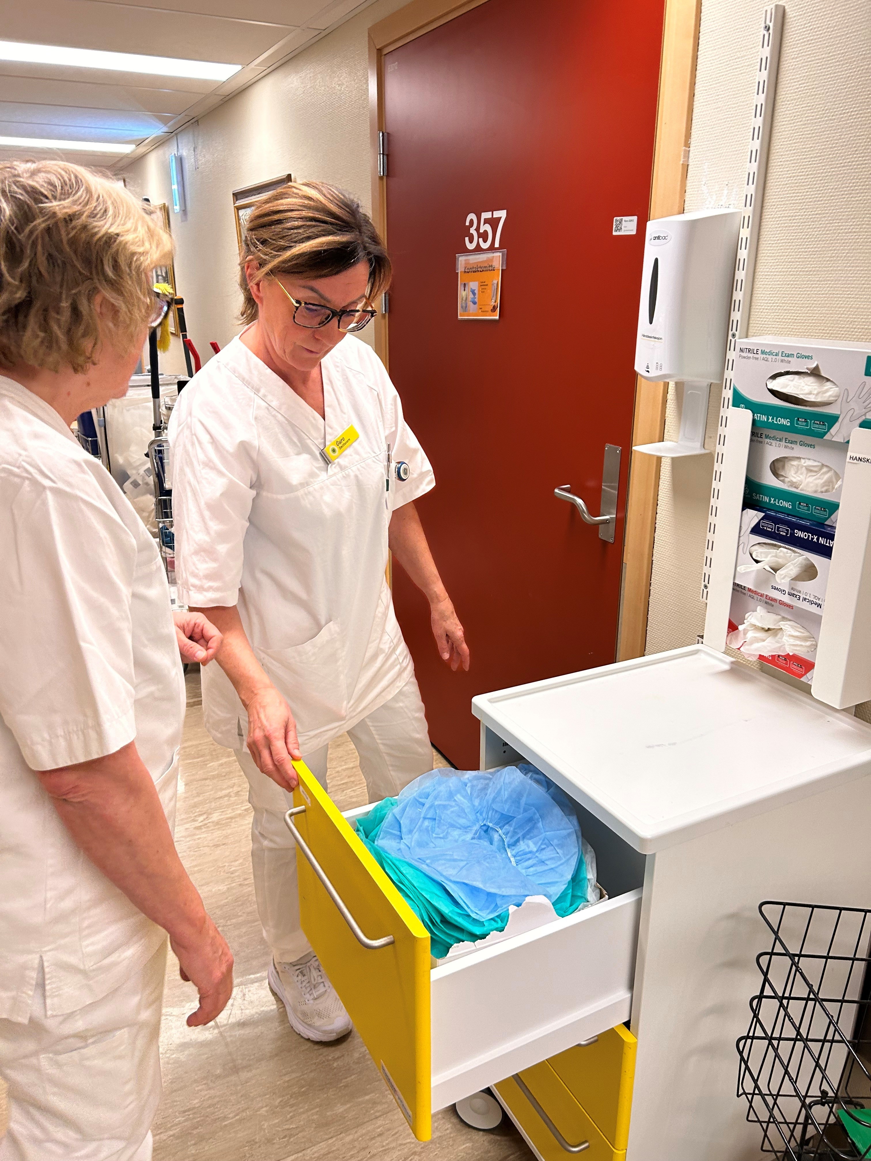 To kvinner ser ned i en skuff med smittevernutstyr