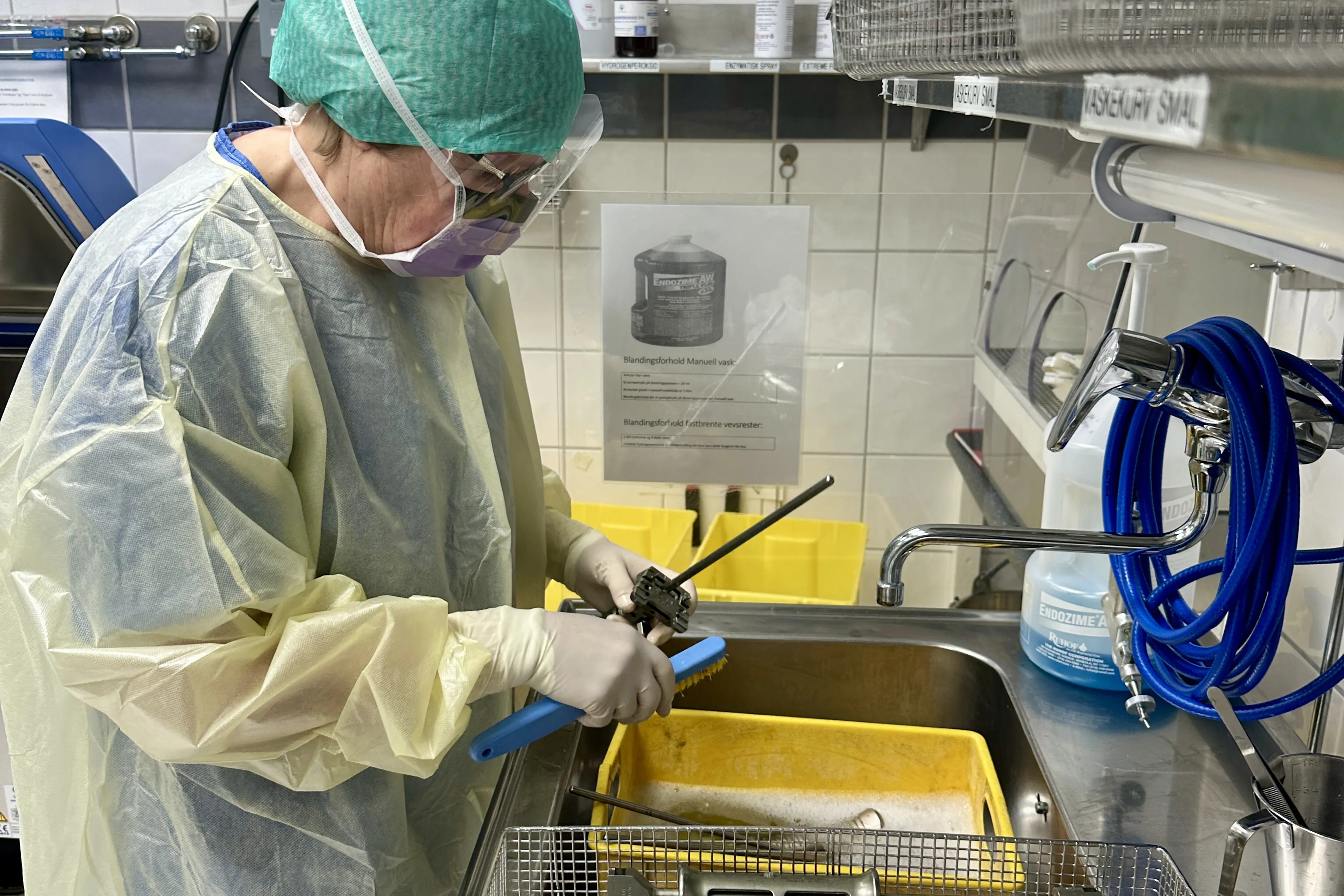 En person i laboratoriefrakk som jobber på en maskin