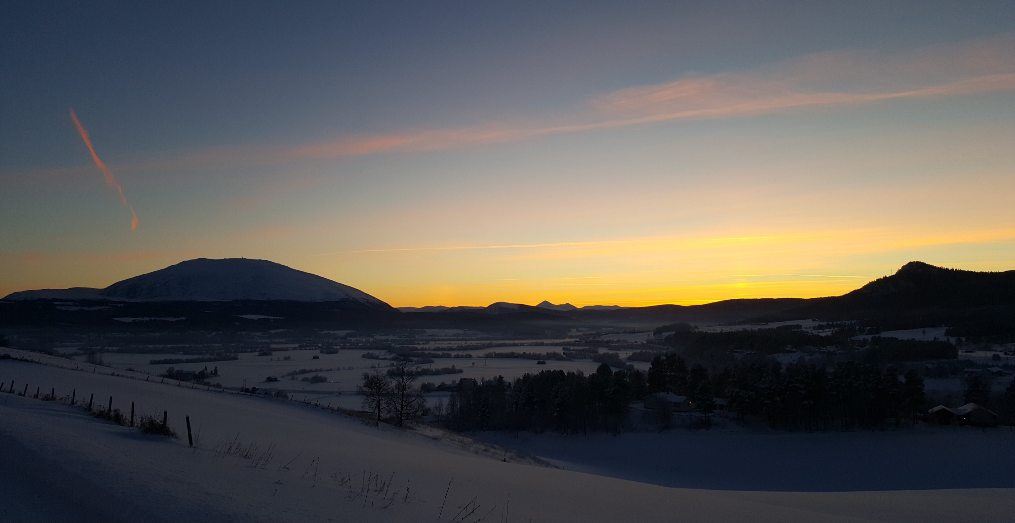 Landskap i Fjellregionen med Tronfjell i det fjerne og solnedgang.