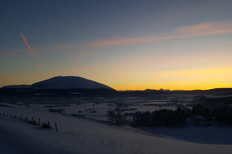 Landskap i Fjellregionen med Tronfjell i det fjerne og solnedgang.