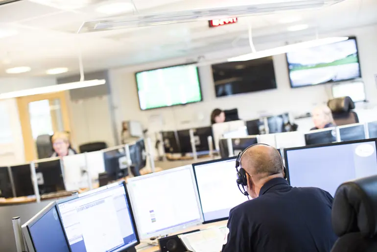 En gruppe mennesker i et rom med datamaskiner
