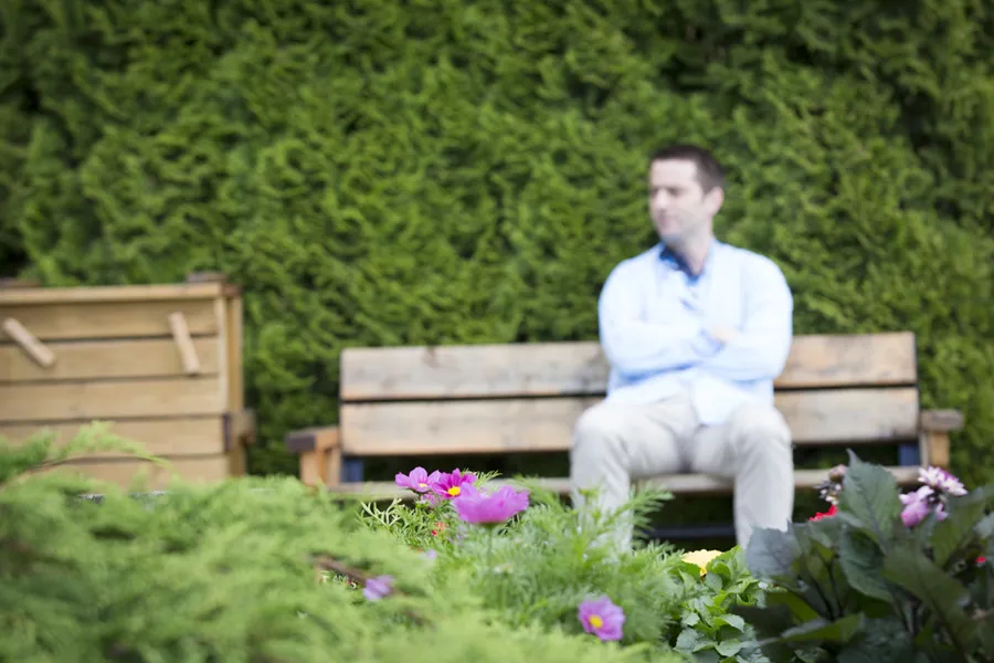 Pasient sitter på en benk utendørs