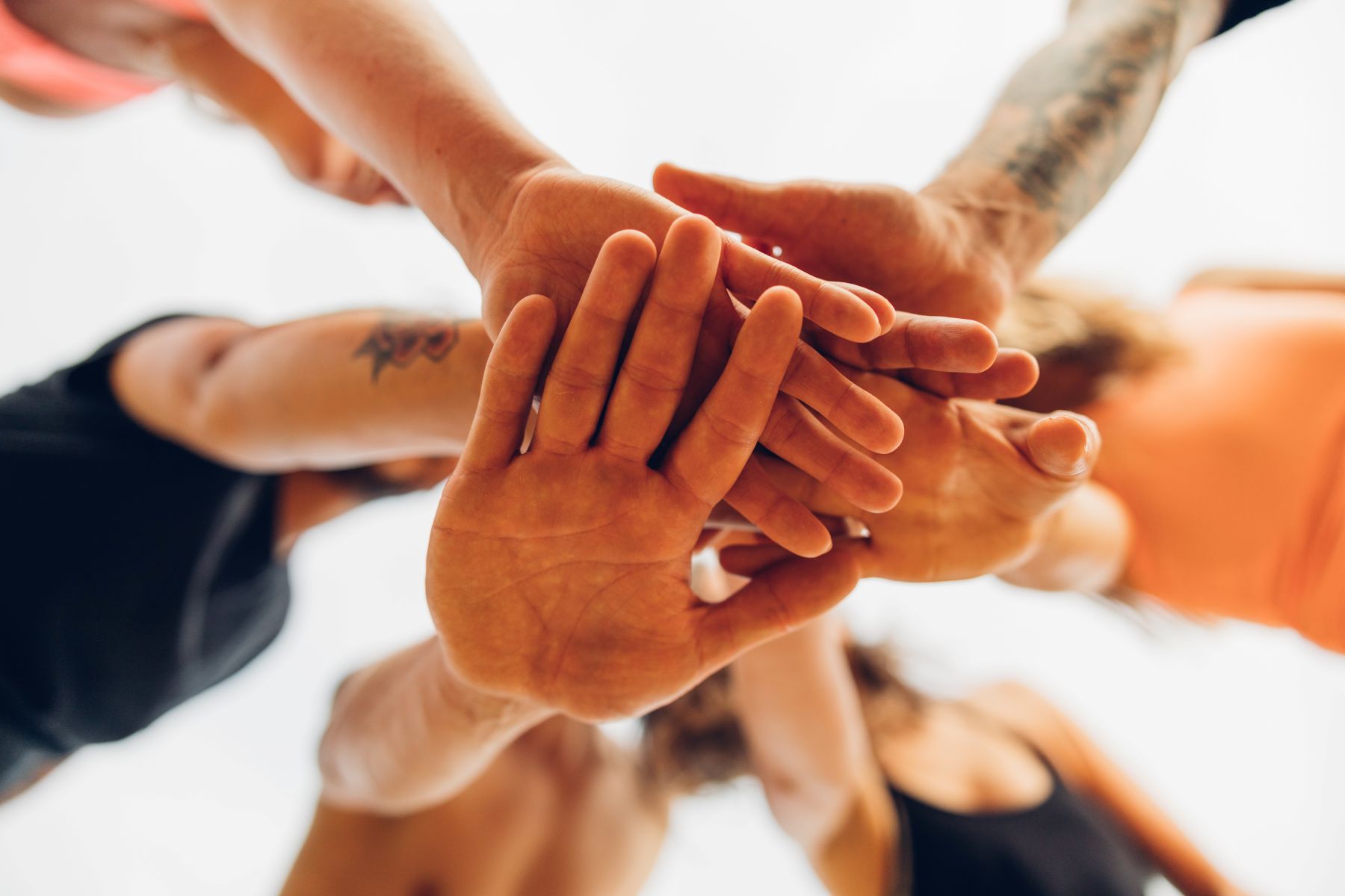 En gruppe mennesker som holder hendene nært hverandre