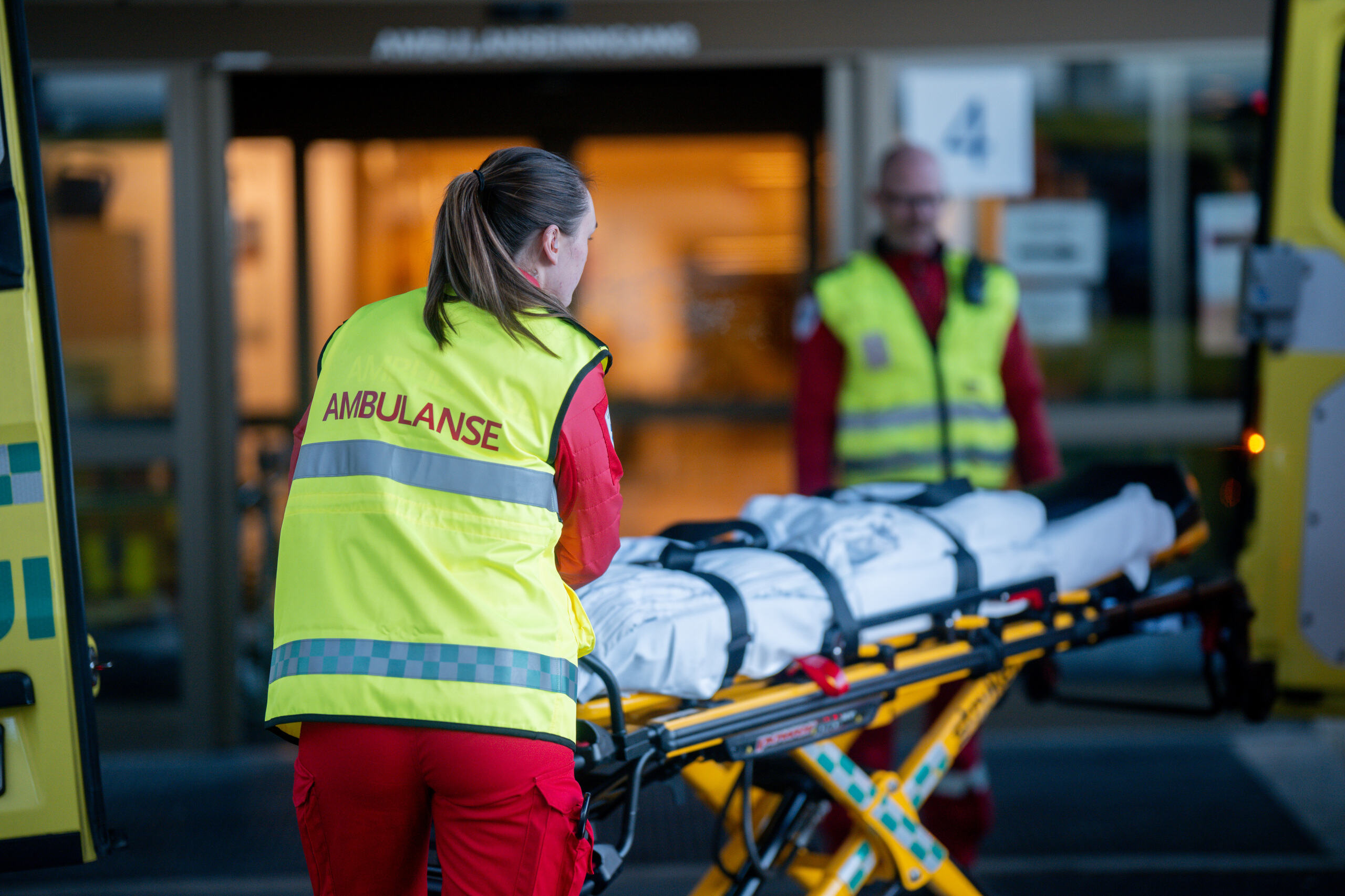 Ambulansepersonell triller inn en pasient fra ambulanse inn på sykehuset