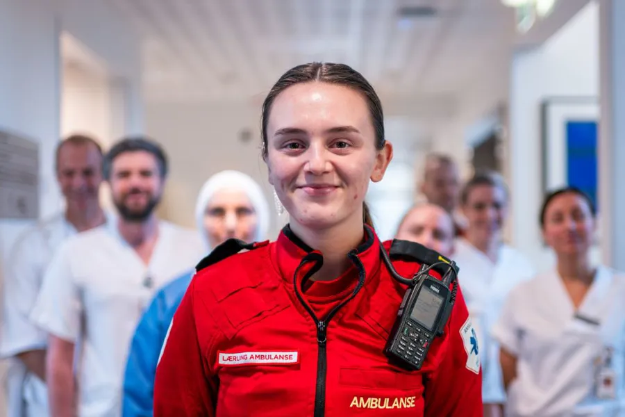 Ambulanselærling i røde ambulanseklær, portrett.