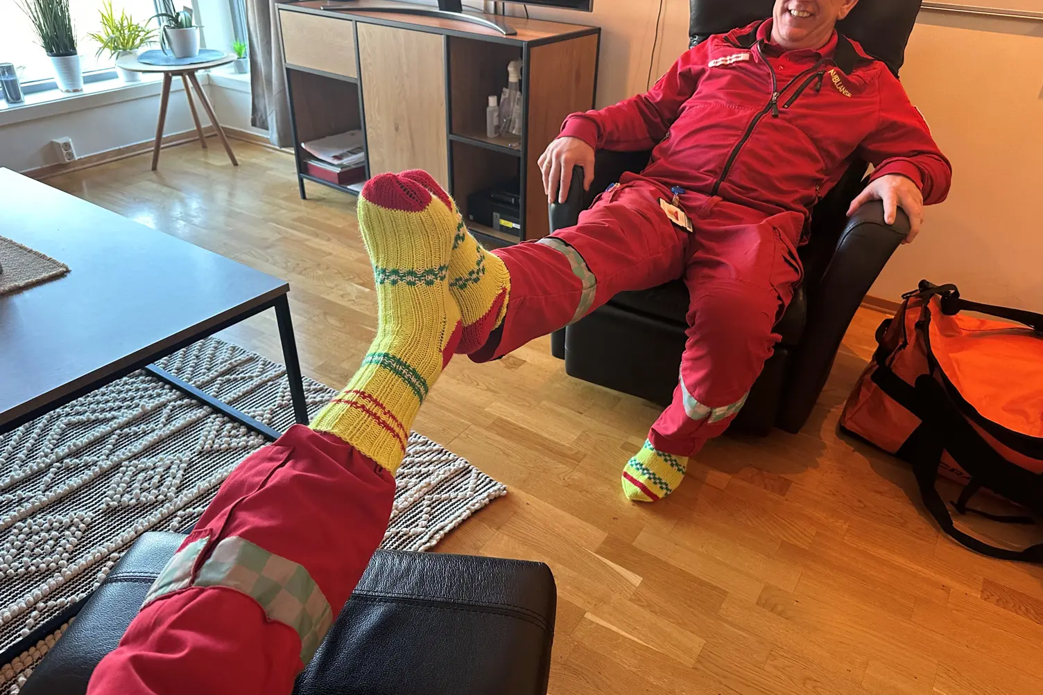 En person i rød dress som sitter på en sofa med et grønt kosedyr