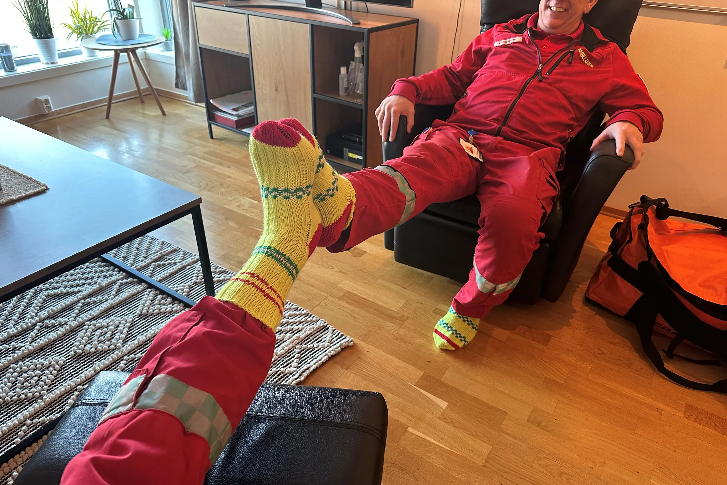 En person i rød dress som sitter på en sofa med et grønt kosedyr