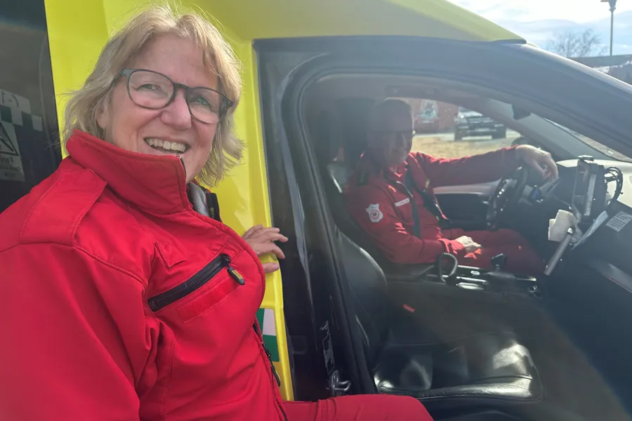 En kvinne i rød frakk som smiler ved siden av en mann i en bil