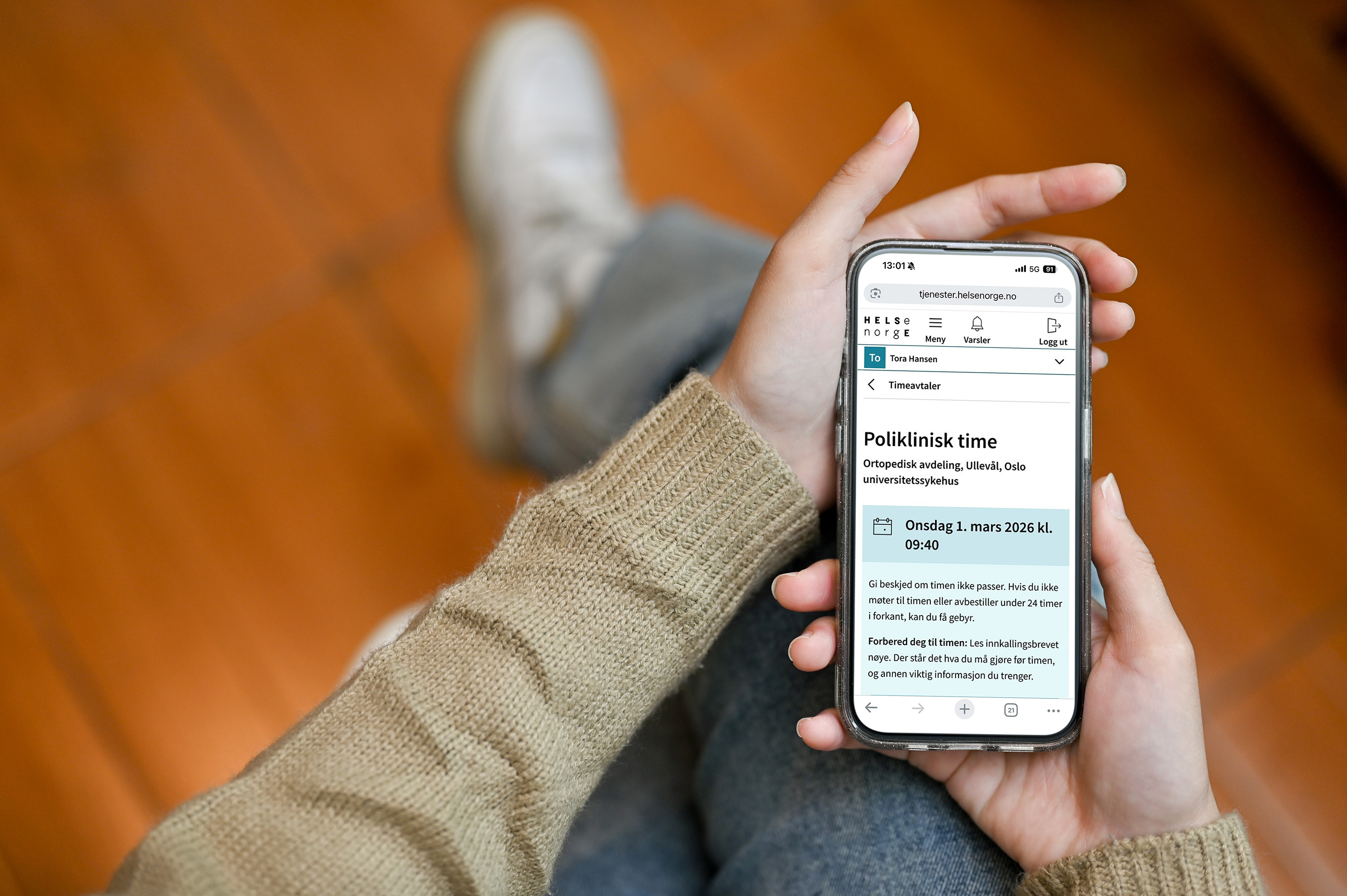 En person holder en telefon med Helsenorge på skjermen
