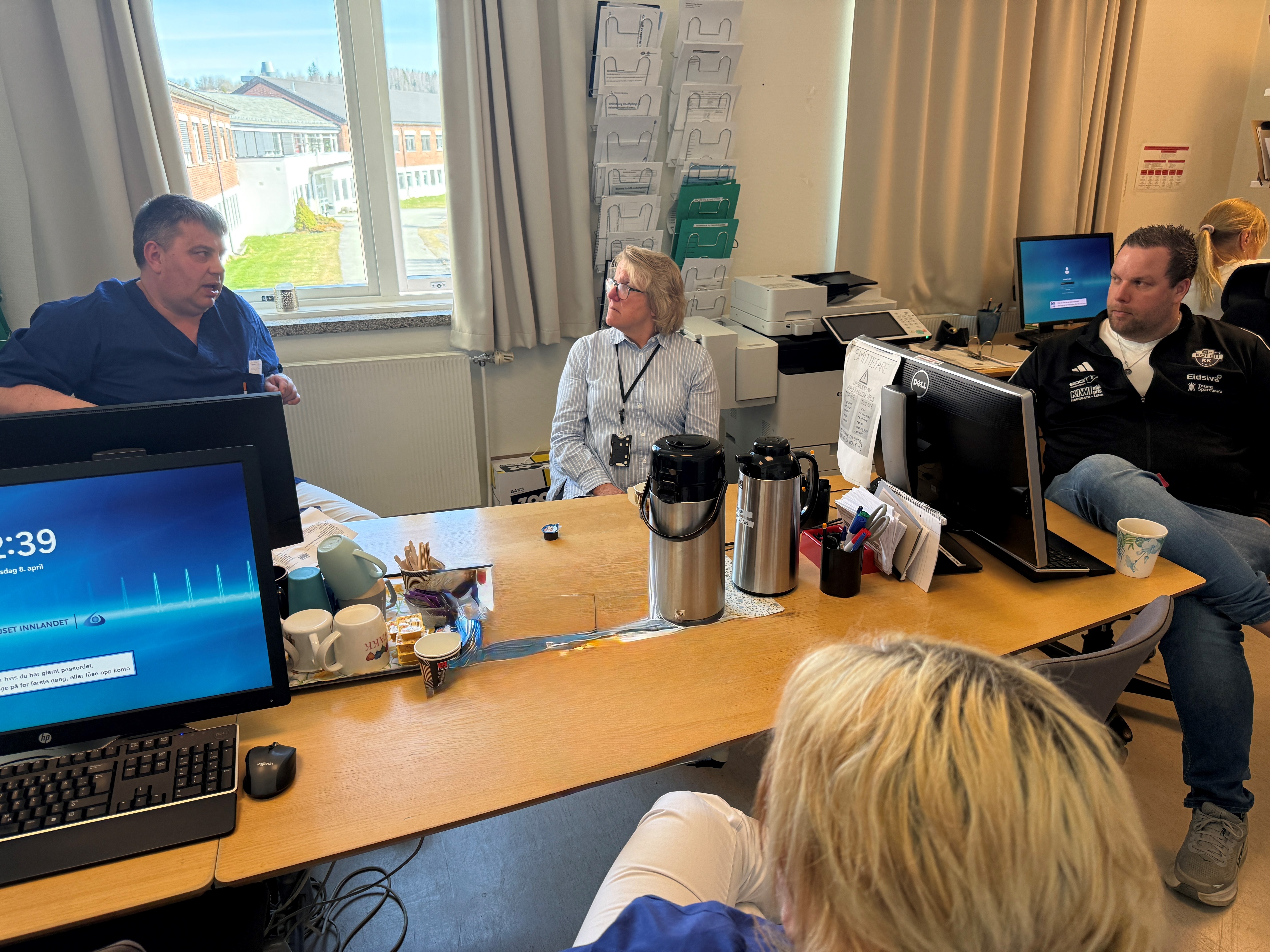 En gruppe mennesker som sitter rundt et bord med datamaskiner