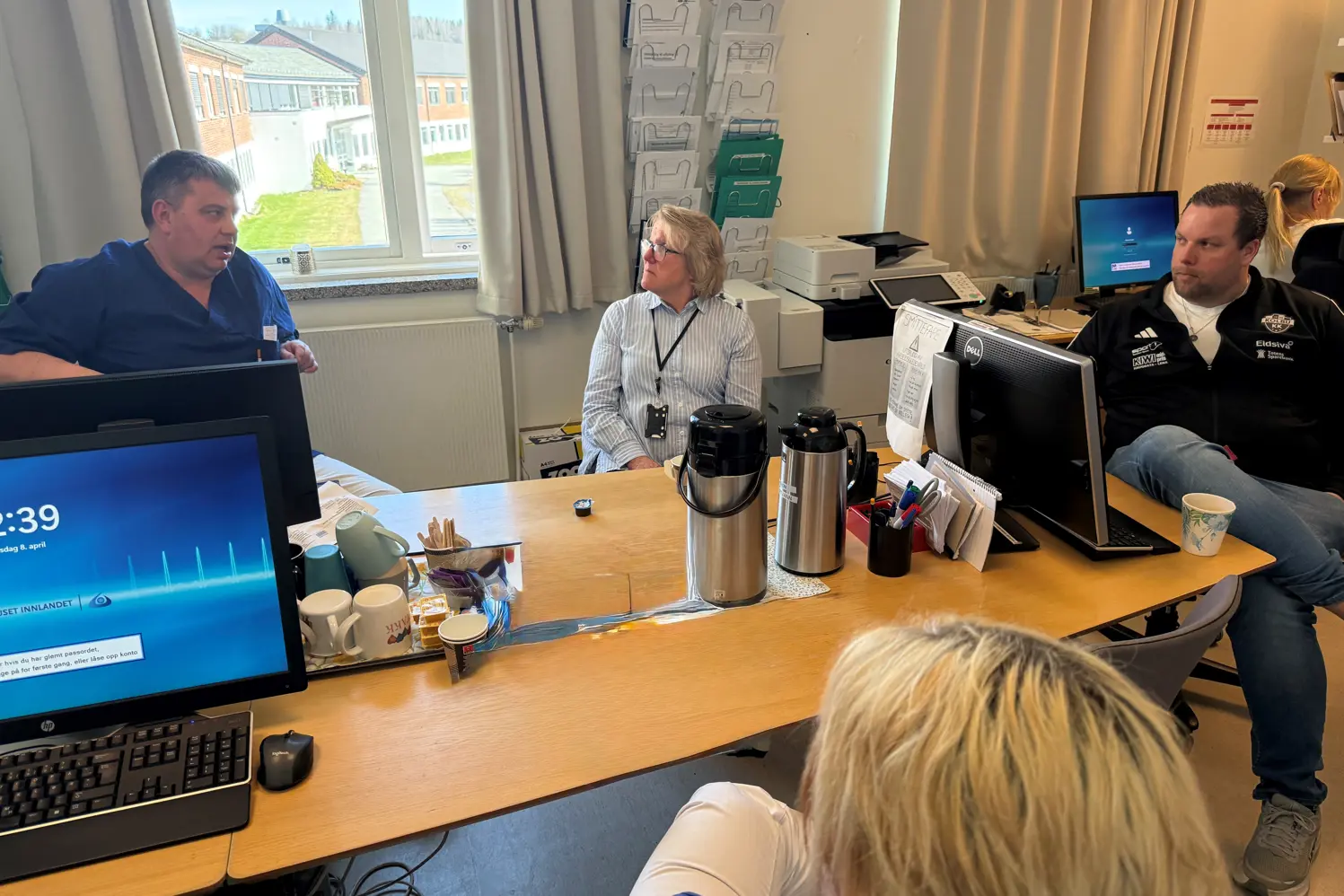 En gruppe mennesker som sitter rundt et bord med datamaskiner