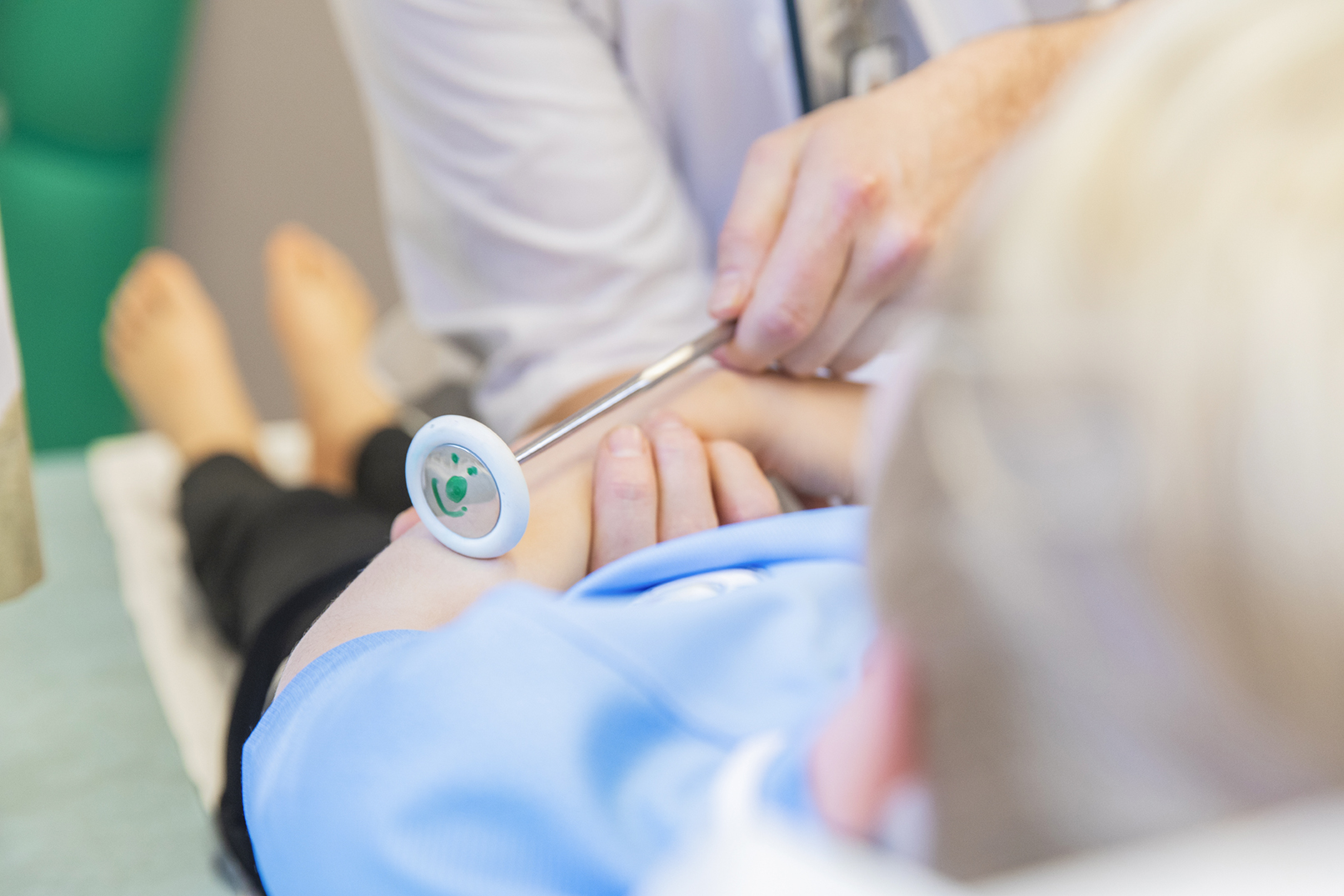 Lege undersøker en gutt med utstyr med et lite smilefjes på.