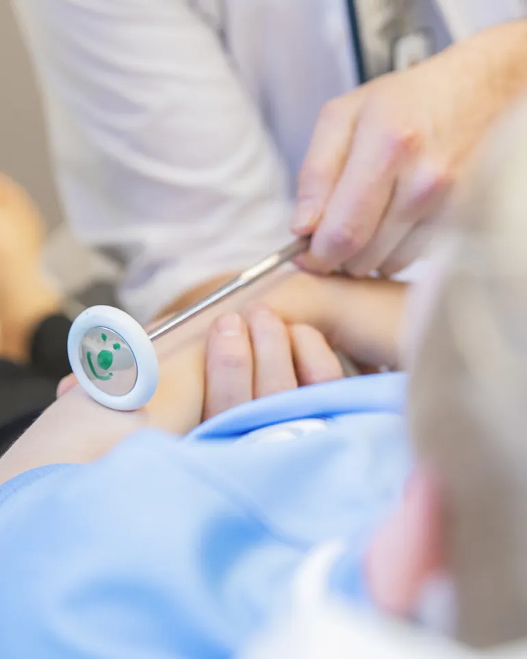 Lege undersøker en gutt med utstyr med et lite smilefjes på.