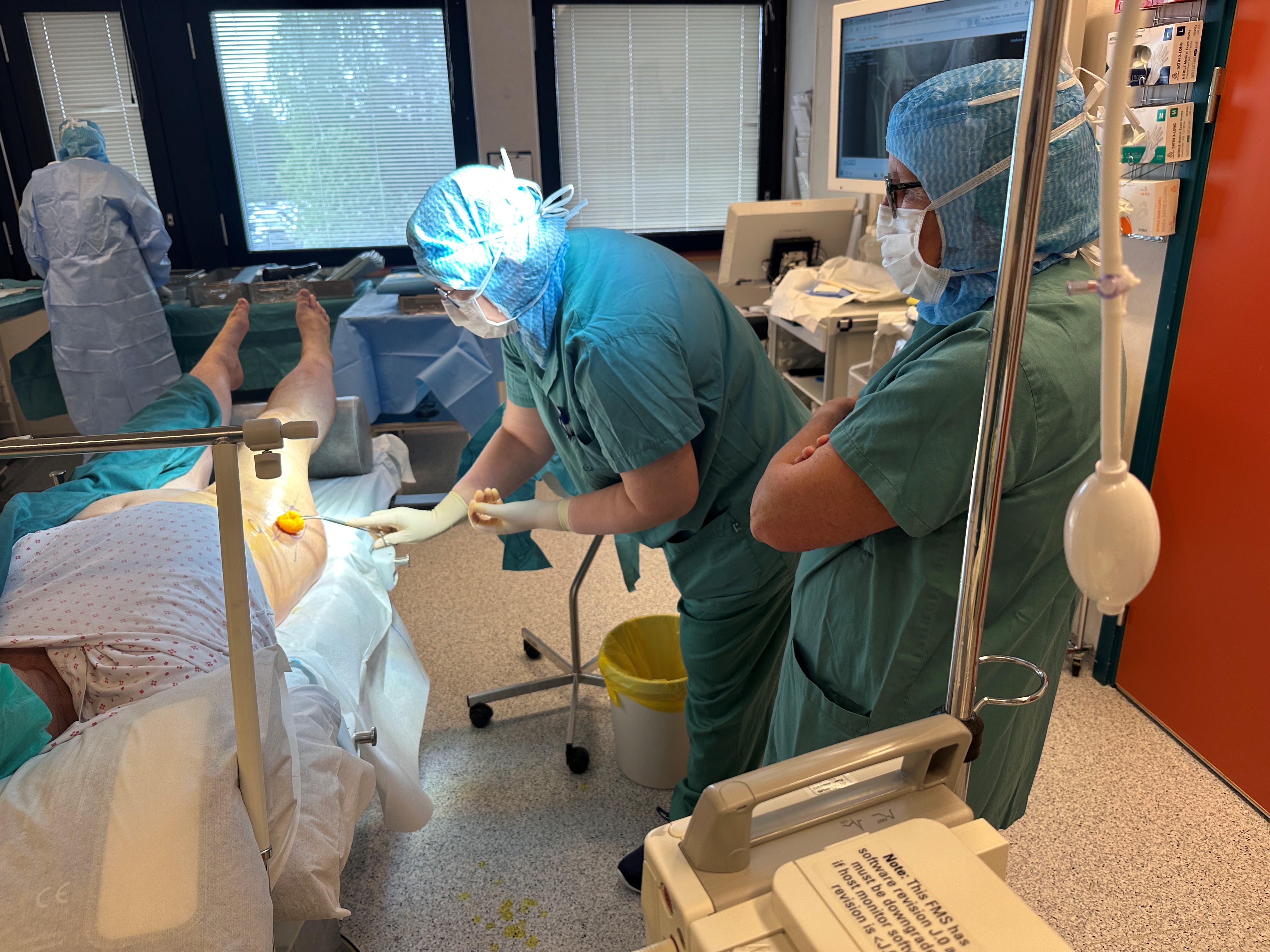 En person i kirurgiske skrubb som jobber med en pasient