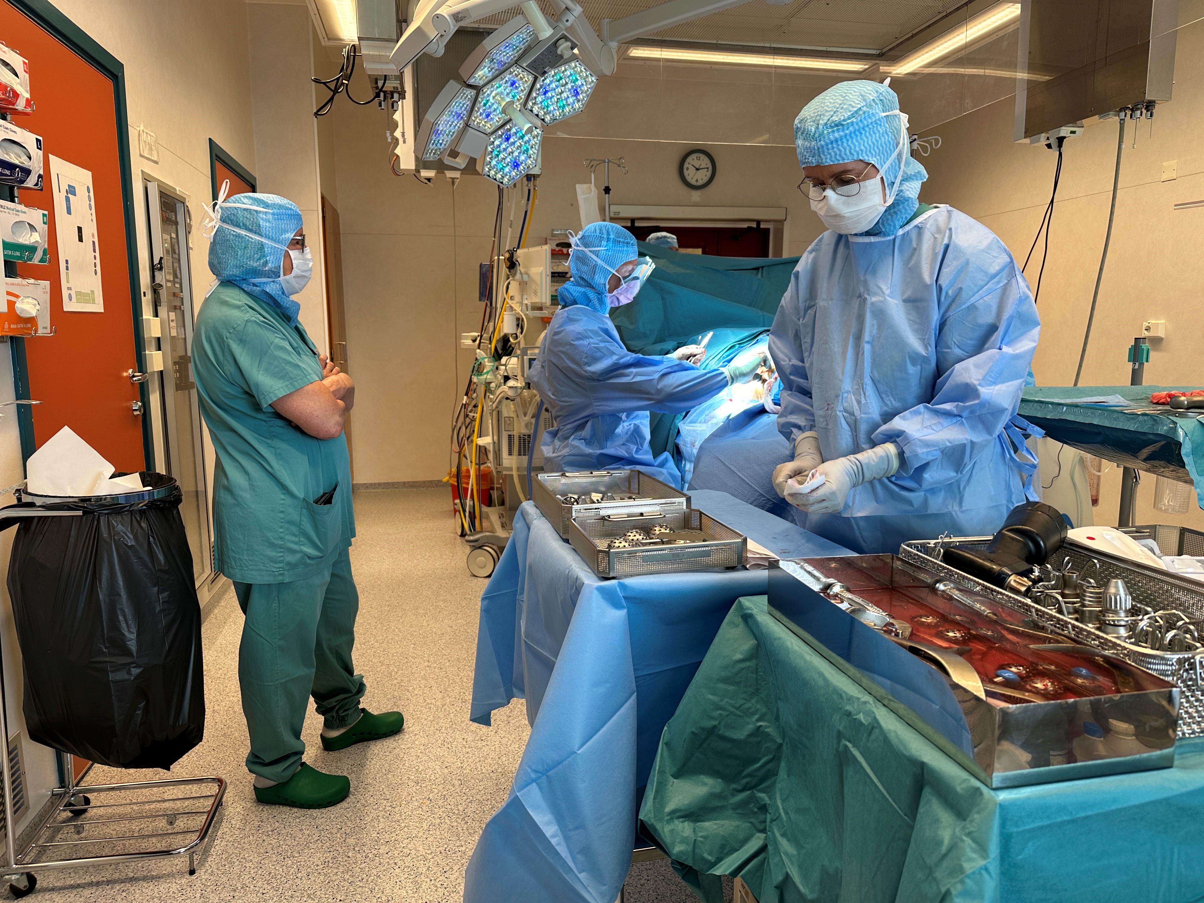 Et par personer i kirurgiske skrubb som jobber på en maskin