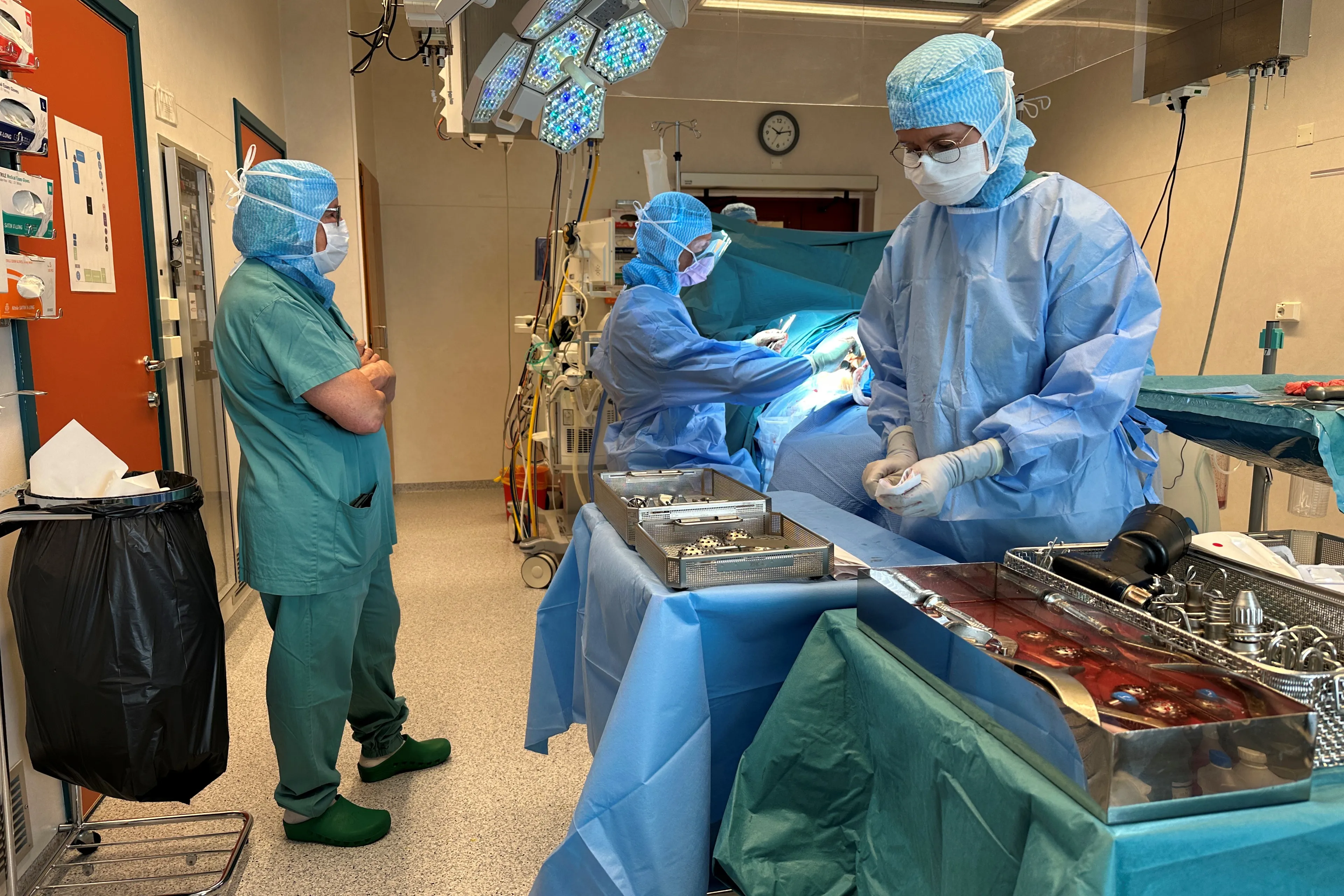 Et par personer i kirurgiske skrubb som jobber på en maskin