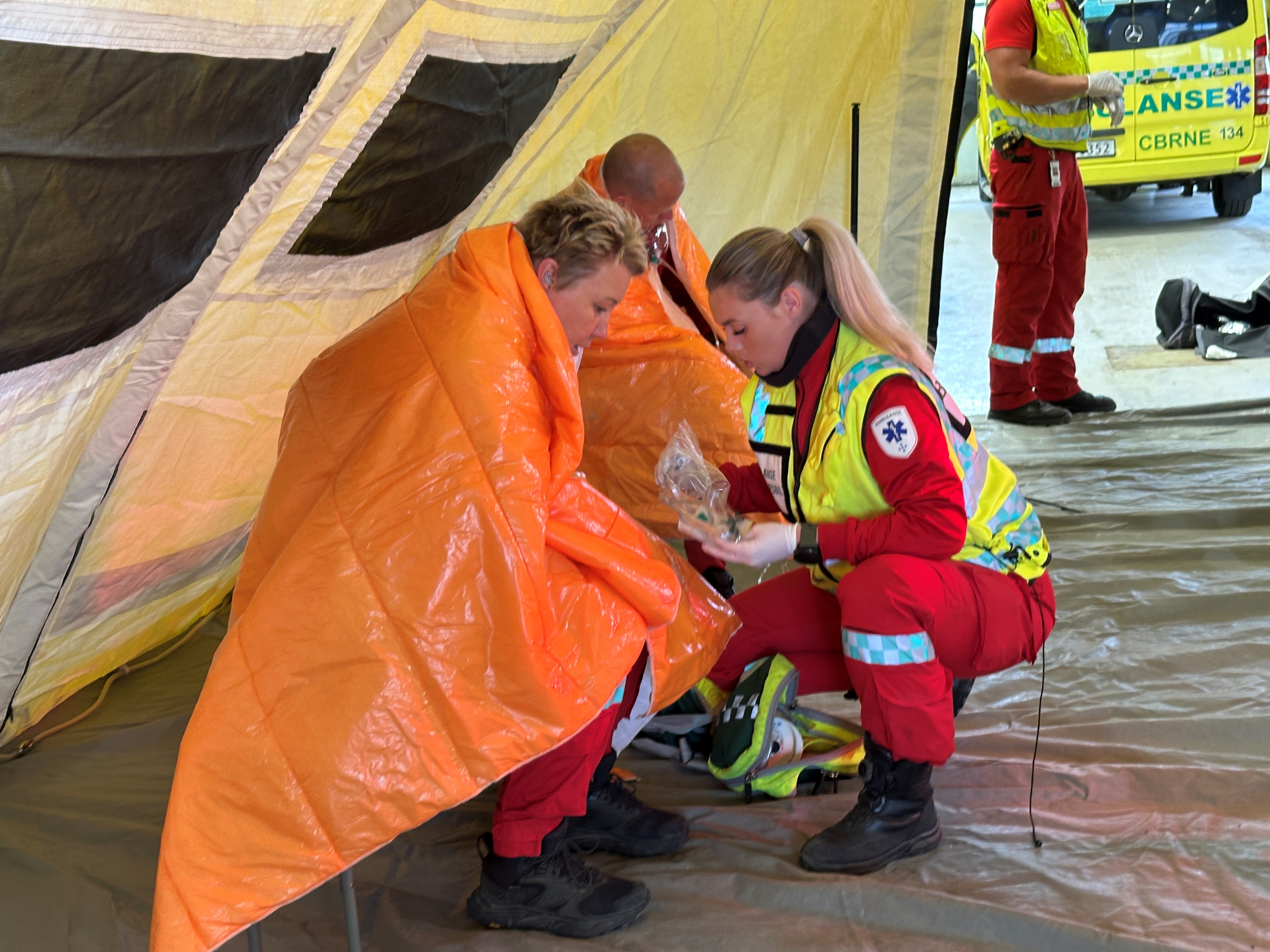 En gruppe mennesker i oransje jumpsuits som holder en stor oransje presenning