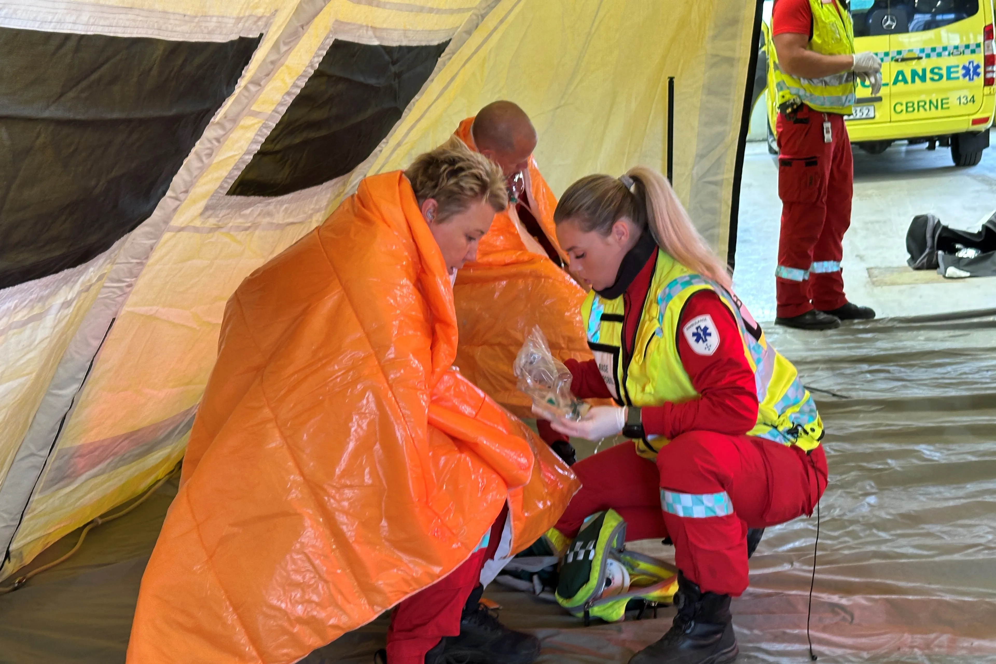 En gruppe mennesker i oransje jumpsuits som holder en stor oransje presenning