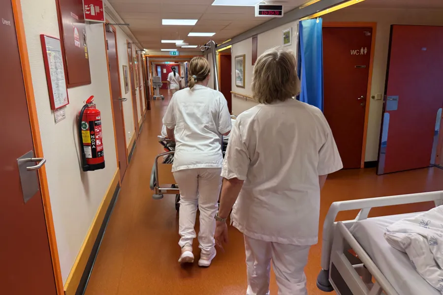 Portør og hospitant med seng i korridor