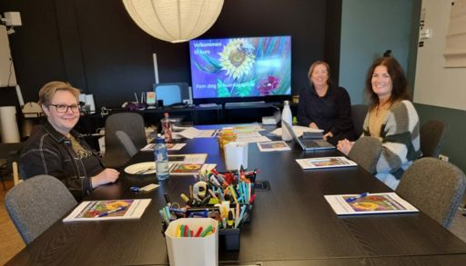 En gruppe kvinner som sitter ved et bord med en datamaskin
