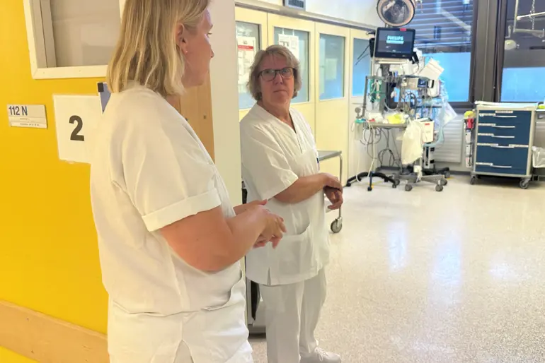 En person i en hvit laboratoriefrakk som snakker med en person i en hvit laboratoriefrakk