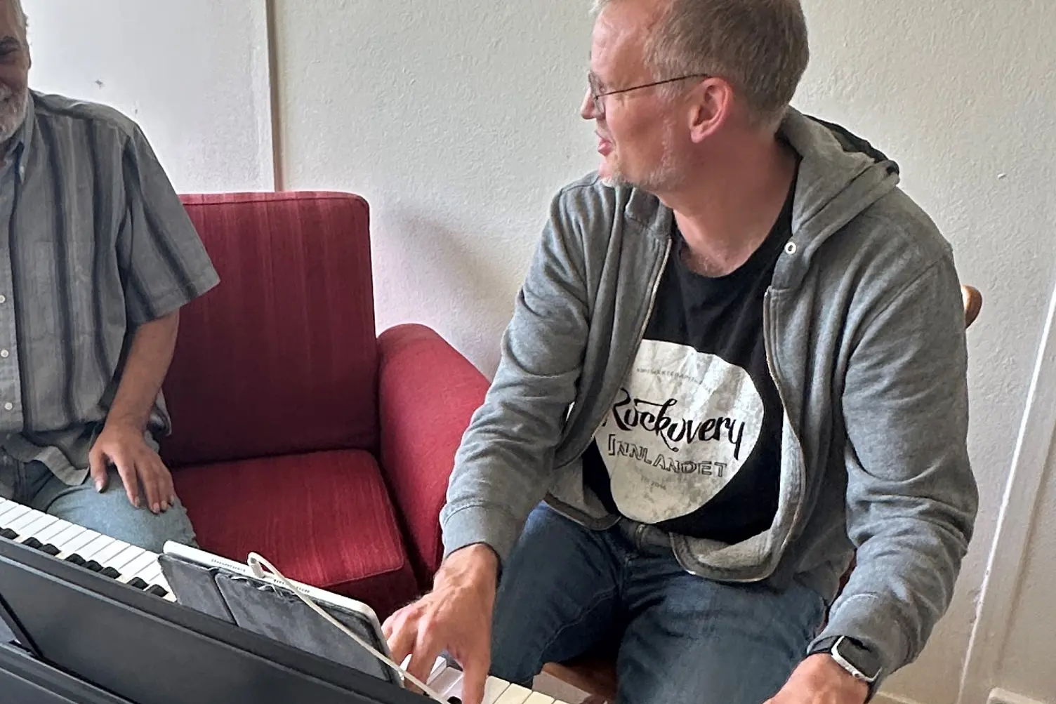 En mann som sitter ved et skrivebord med et tastatur og en bærbar datamaskin