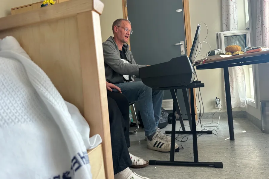 En person som sitter på en stol med en bærbar datamaskin foran seg