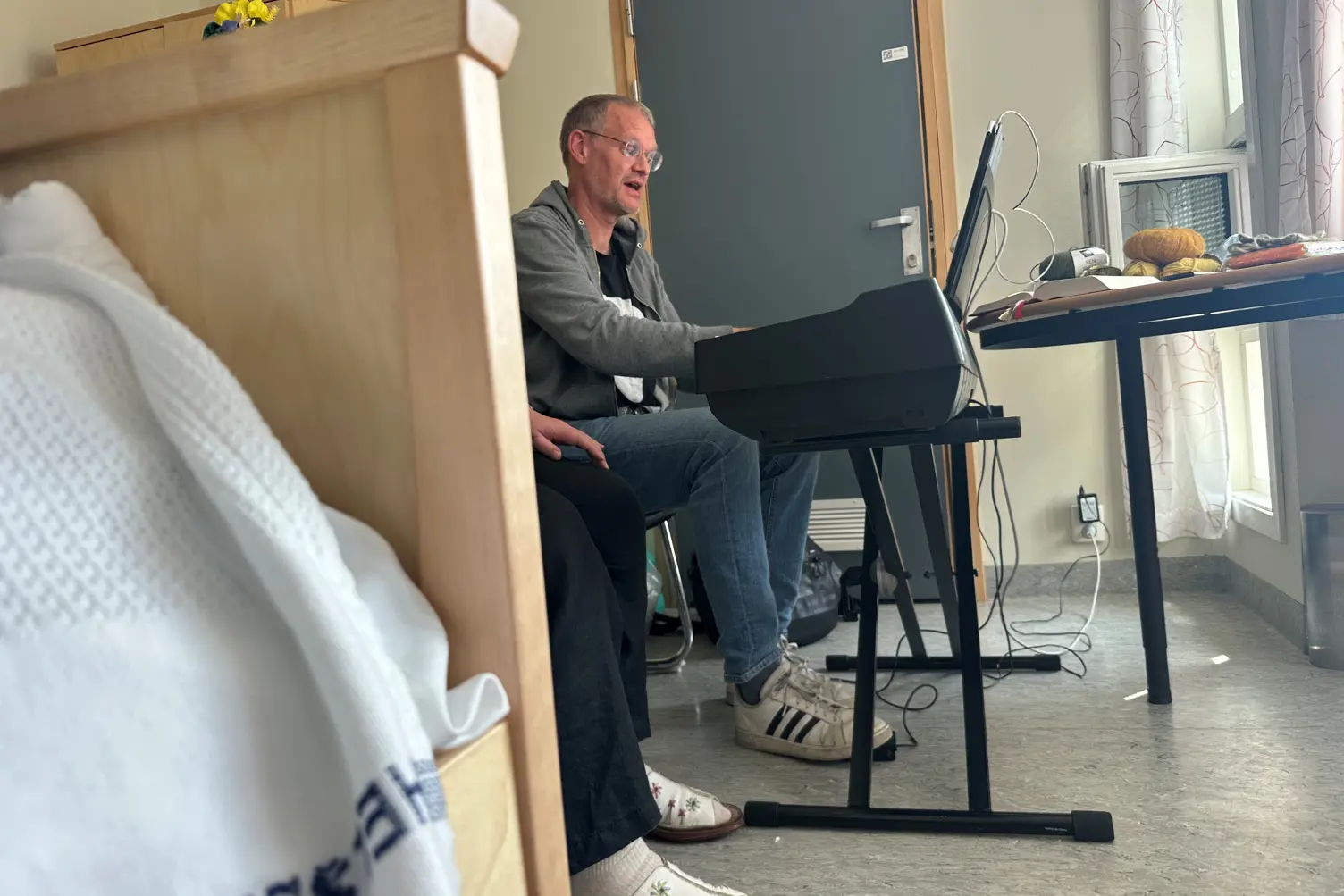 En person som sitter på en stol med en bærbar datamaskin foran seg