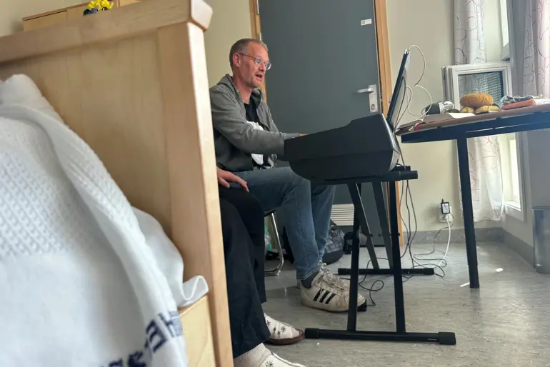 En person som sitter på en stol med en bærbar datamaskin foran seg