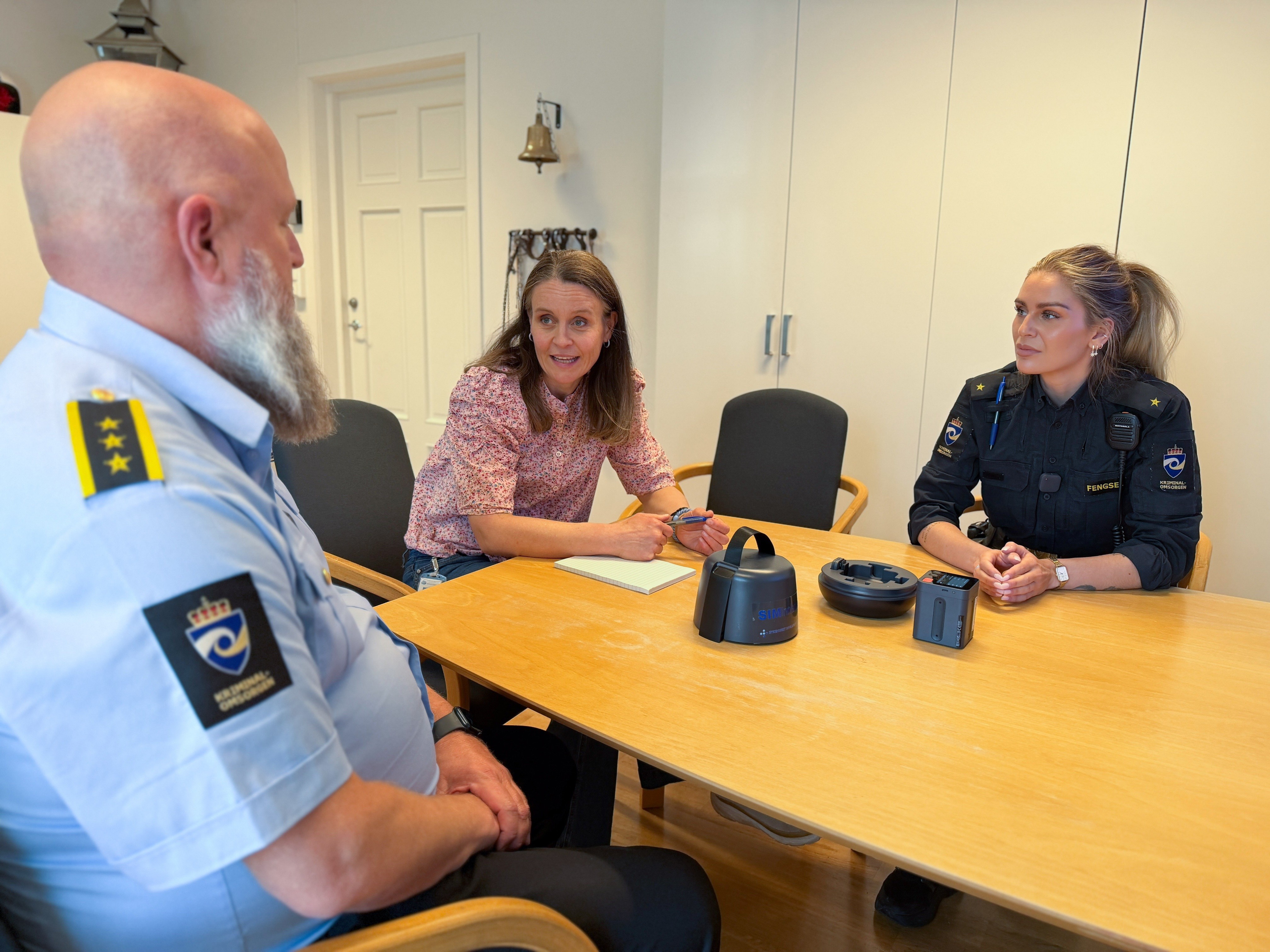 To fengselsbetjenter og programleder for podkasten rundt et bord