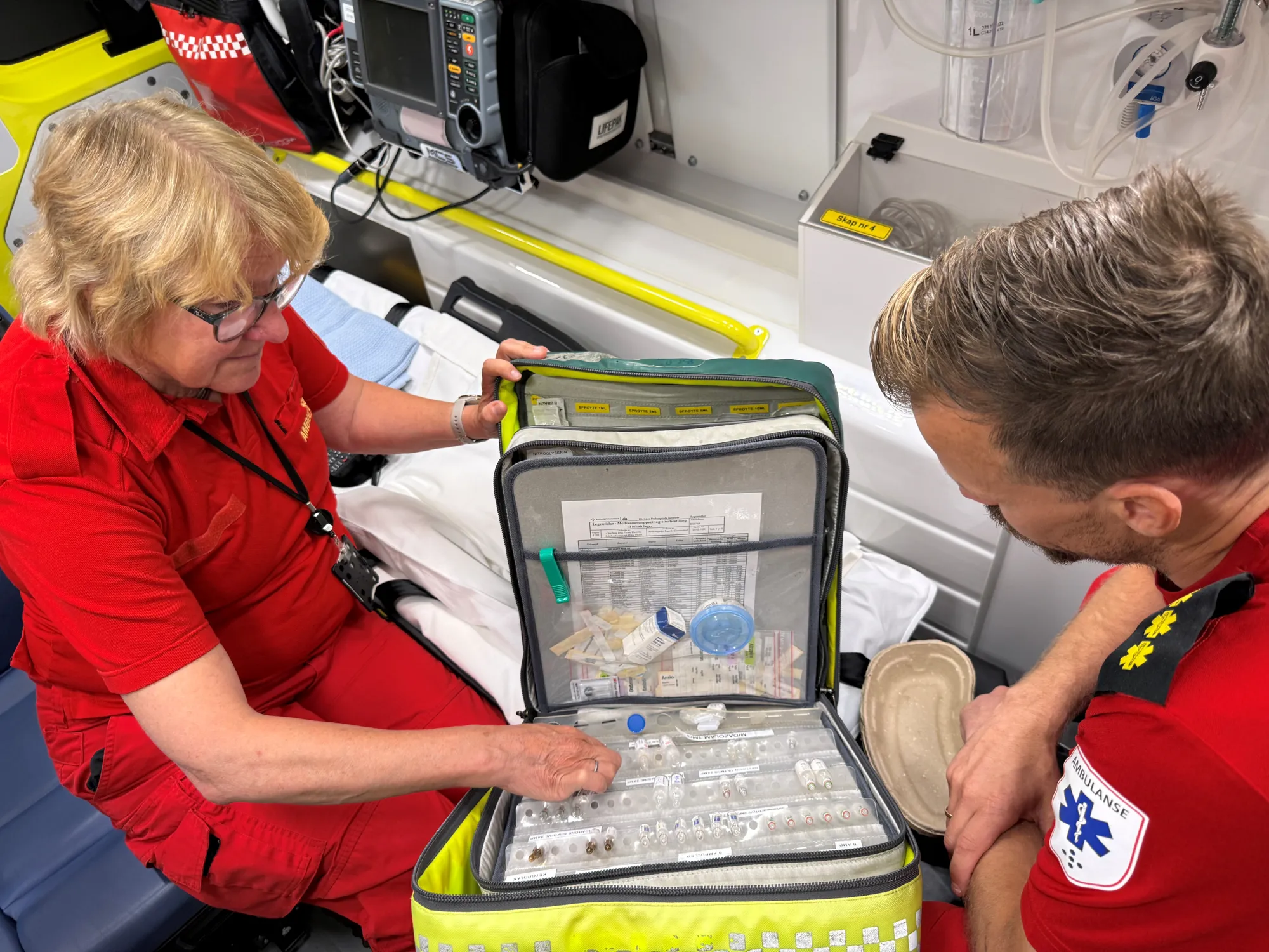 Ambulansearbeider og hospitant går gjennom medikamentveske i ambulanse.