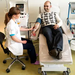 Blodgiver under tapping med helsepersonell ved siden av seg, illustrasjonsfoto
