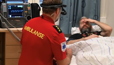 Ambulansearbeider med hodekamera i interaksjon med pasient.