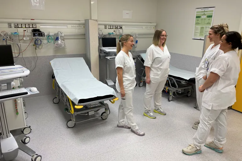 Fire blide sykepleiere snakker med hverandre i moderniserte lokaler.