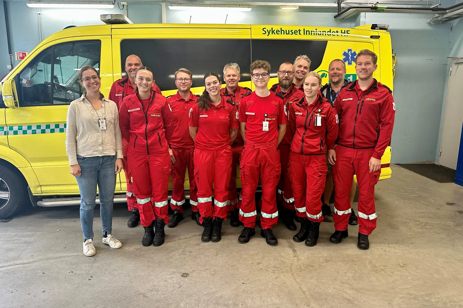 En gruppe mennesker i røde jumpsuits som står foran en gul lastebil