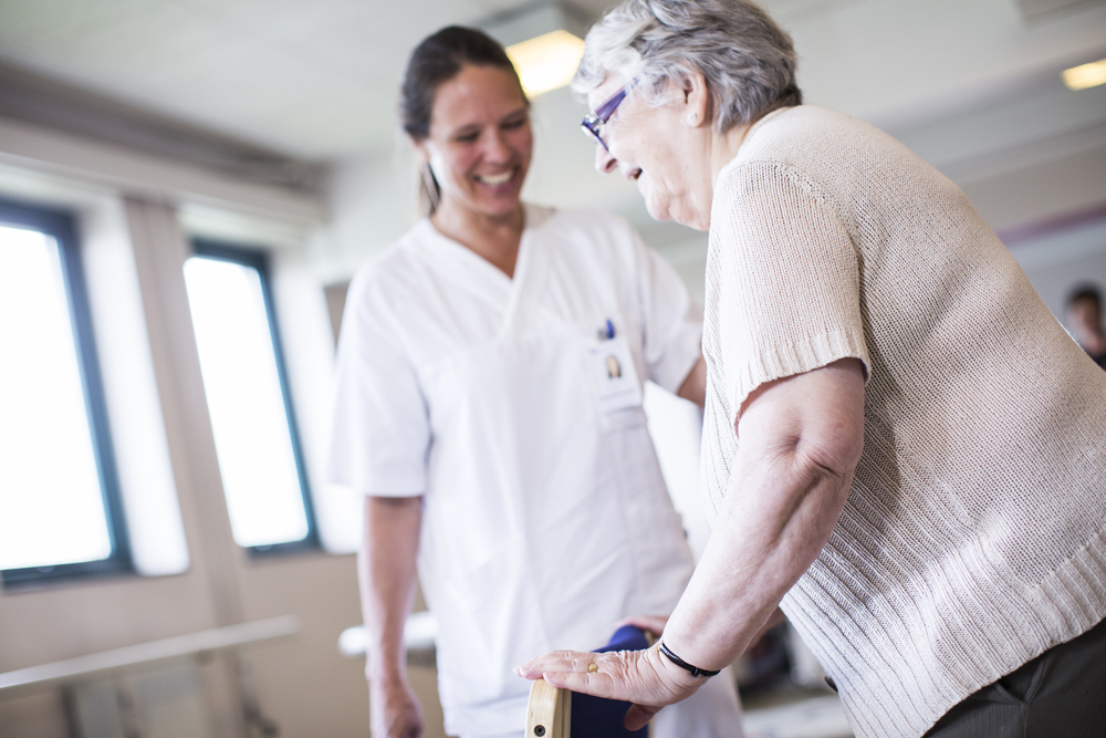 Eldre pasient og ansatt i hvitt.