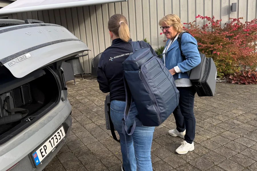 En gruppe mennesker som går forbi en bil