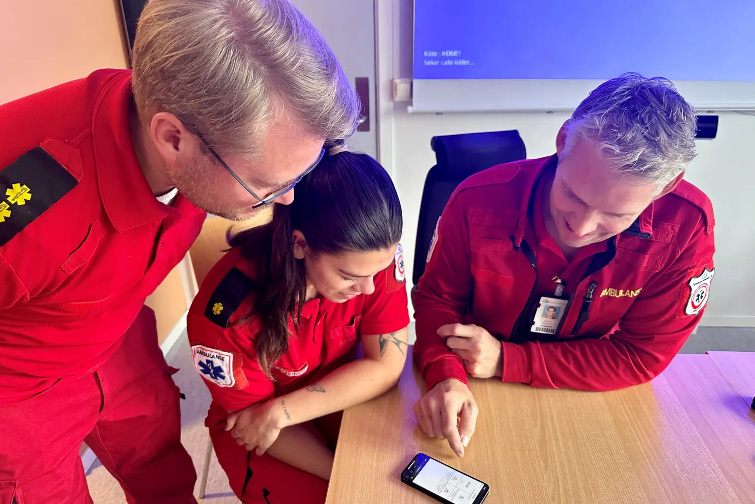 En gruppe mennesker som ser på en mobiltelefon