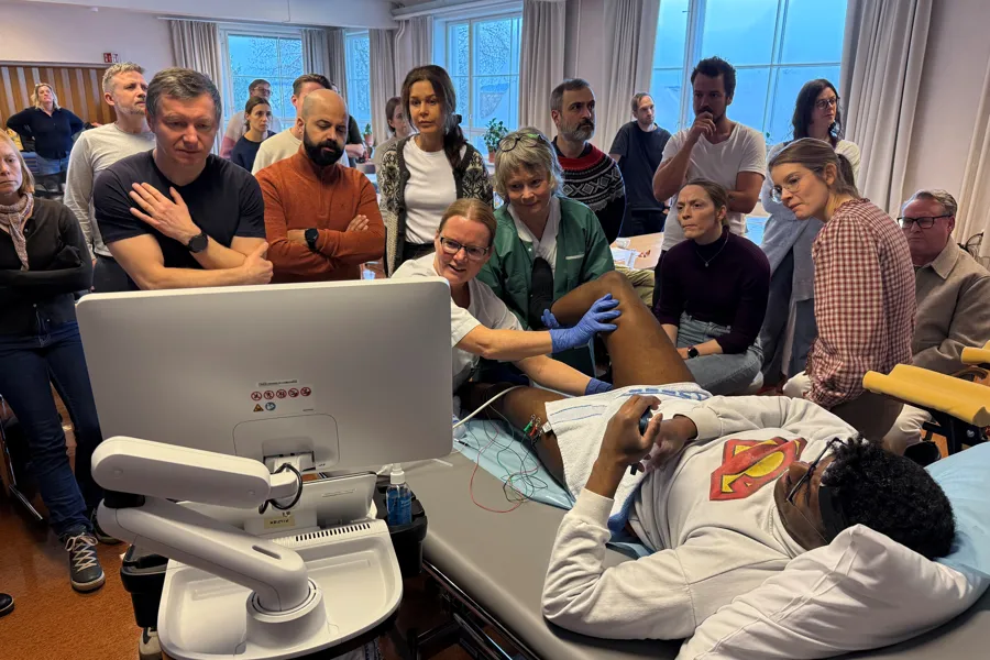 Lege Kristin Østlie demonstrerer injeksjon på pasient foran alle kursdeltakere.