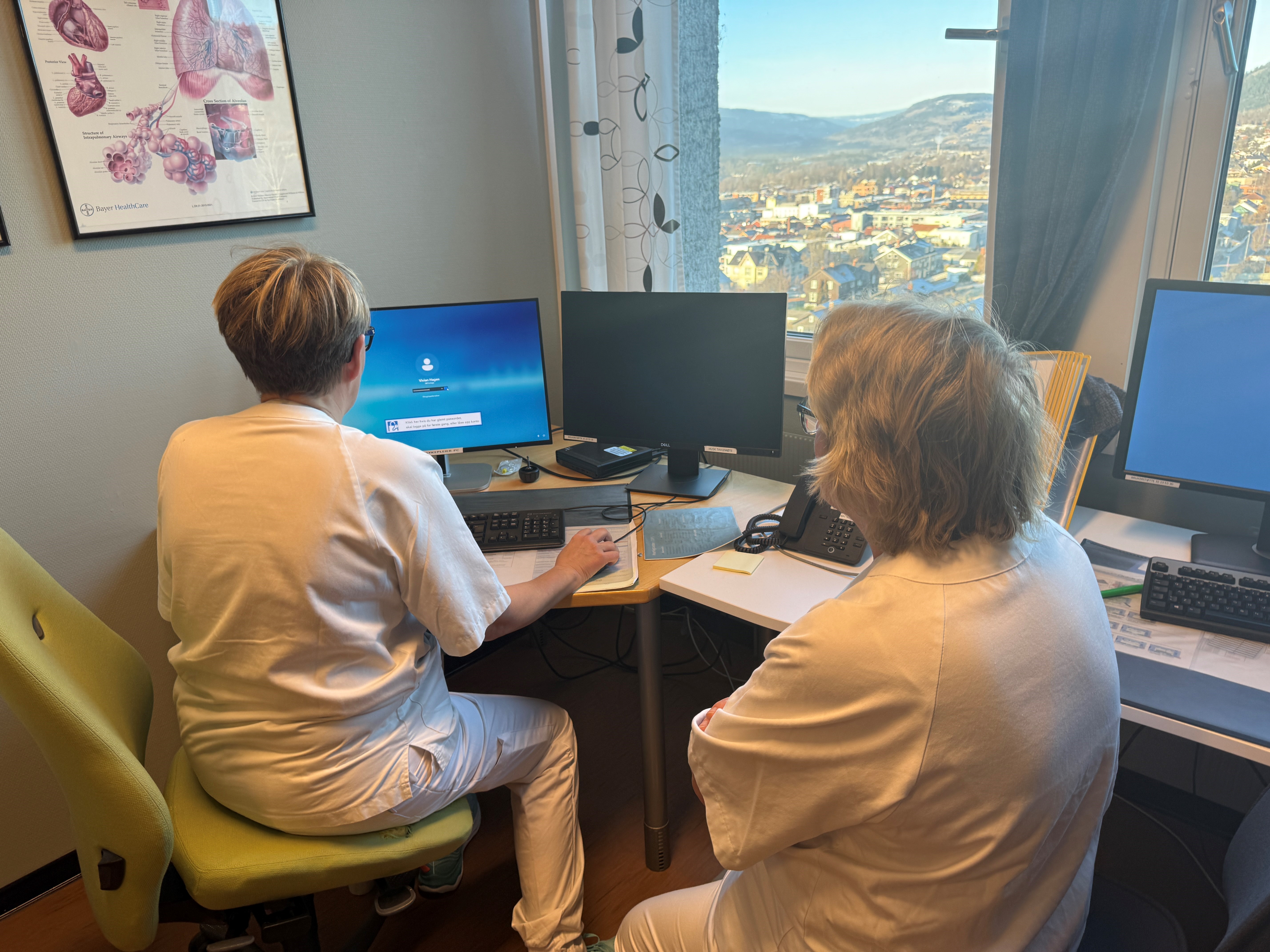 En mann og en kvinne som sitter ved et skrivebord med datamaskiner