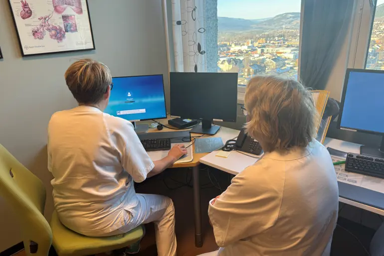 En mann og en kvinne som sitter ved et skrivebord med datamaskiner
