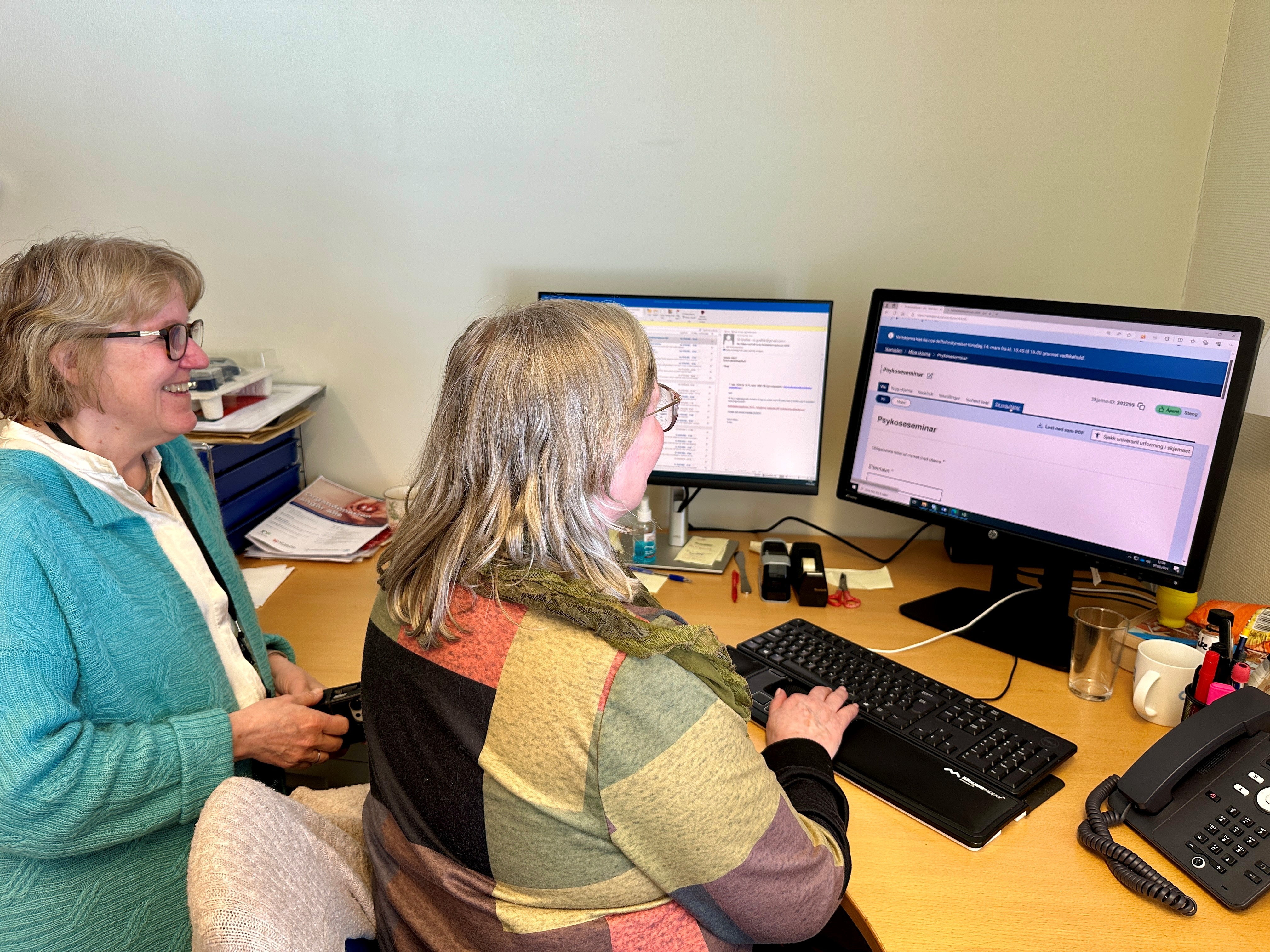 Kvinner som sitter ved et skrivebord med datamaskiner