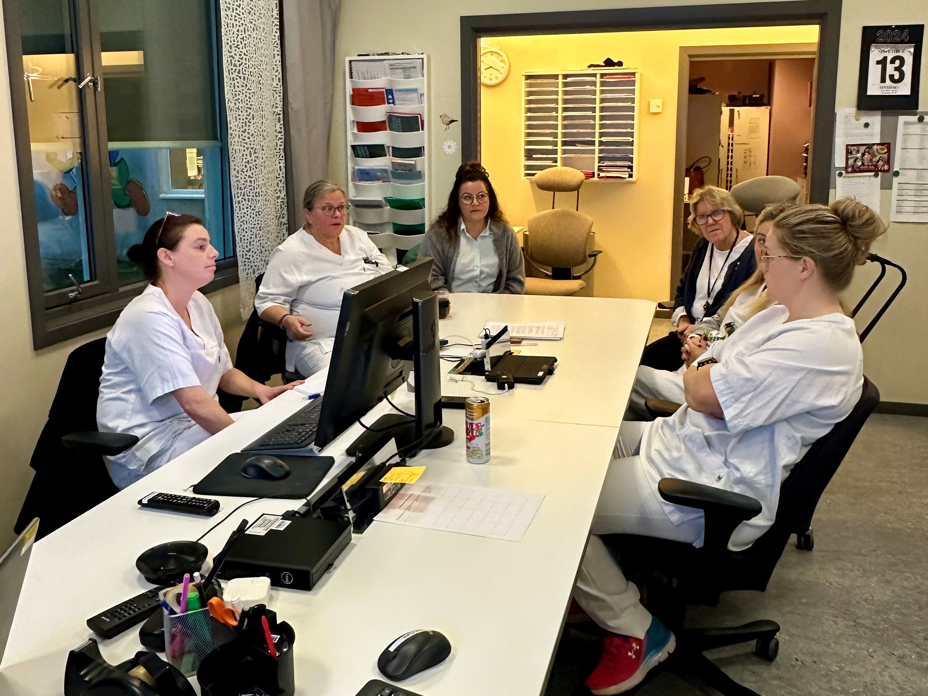 En gruppe mennesker som sitter rundt et bord med datamaskiner