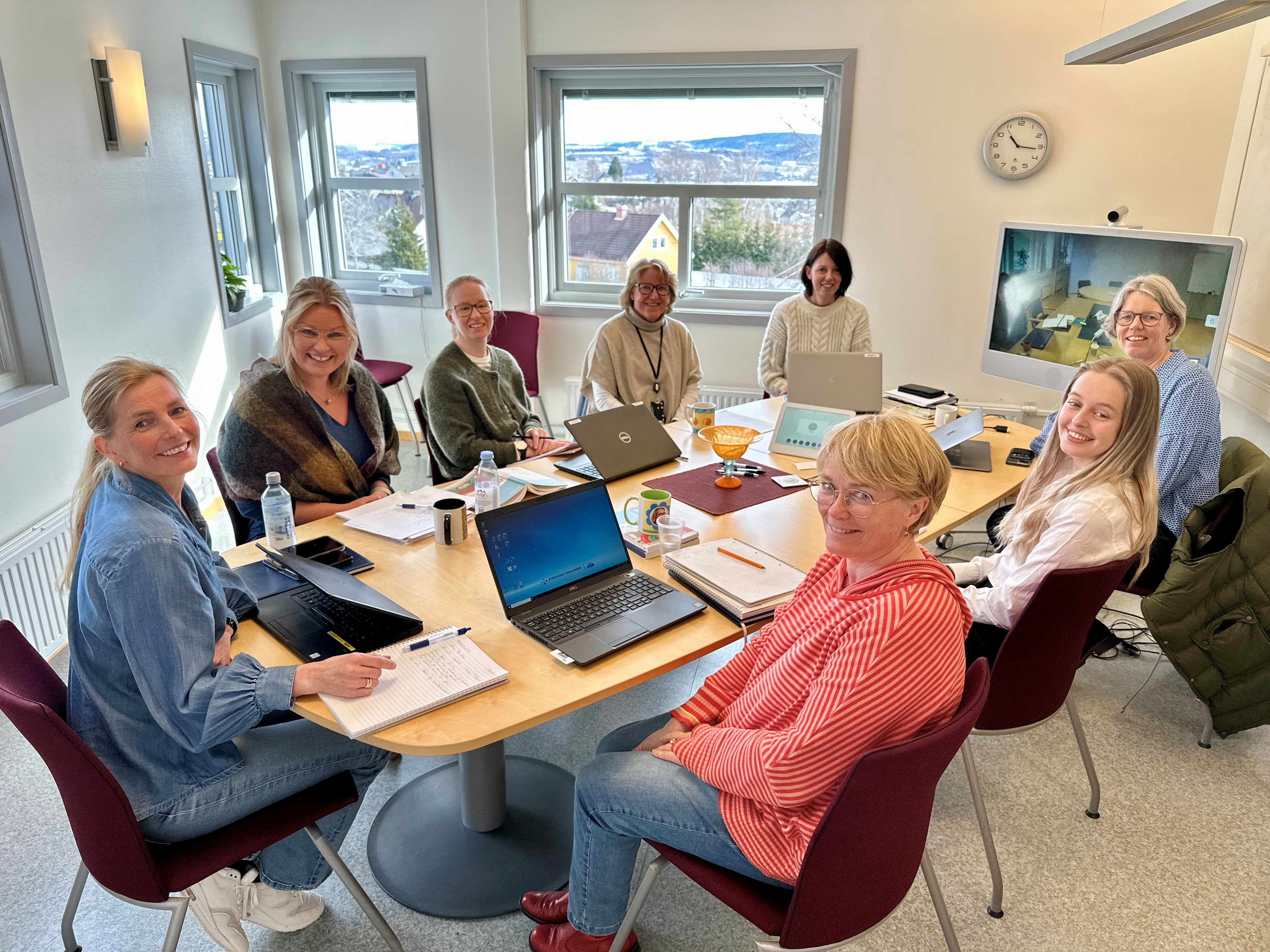 En gruppe mennesker som sitter rundt et bord med bærbare datamaskiner