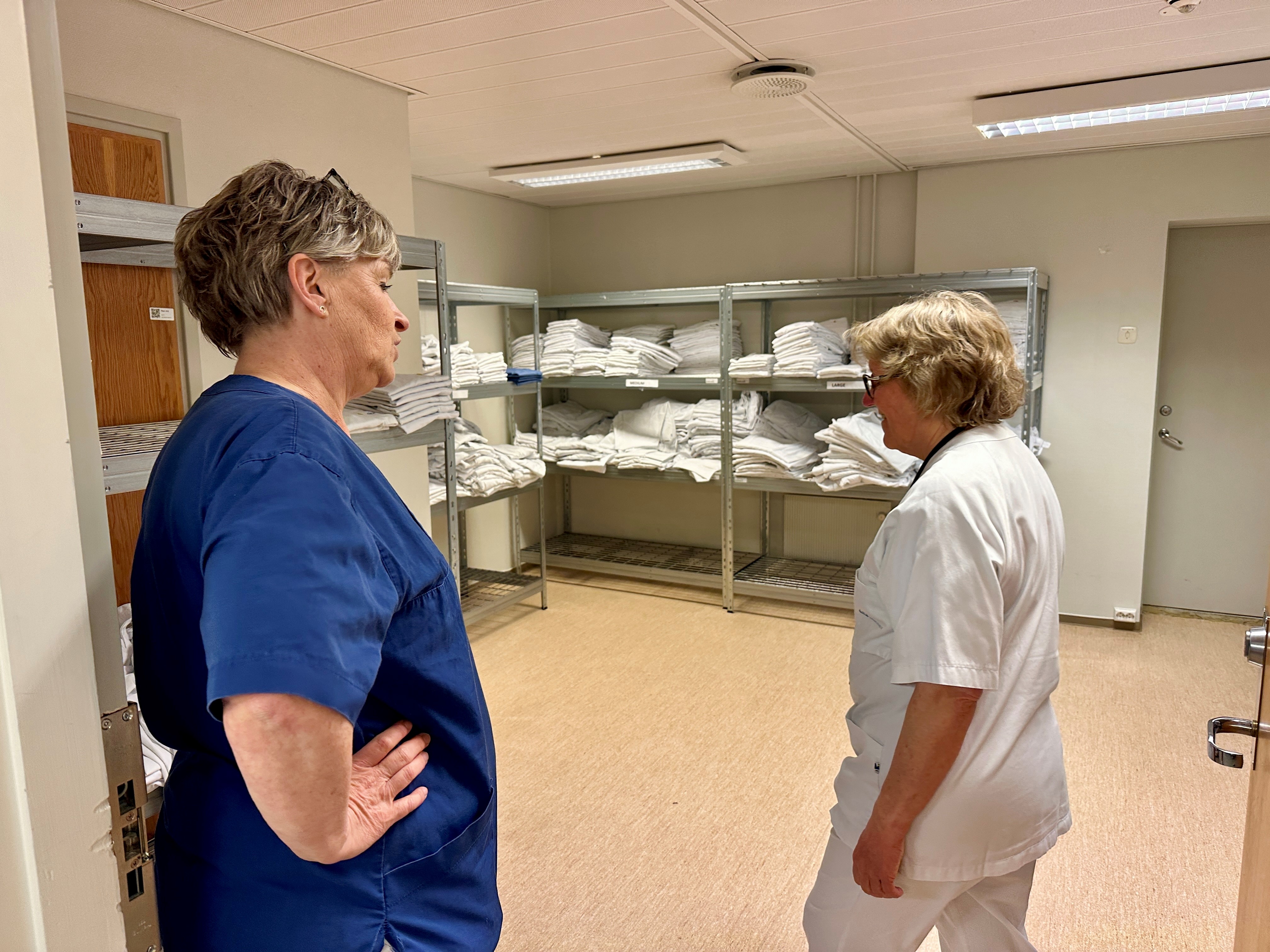 En mann og en kvinne som snakker i et rom med hyller og en vegg av sko